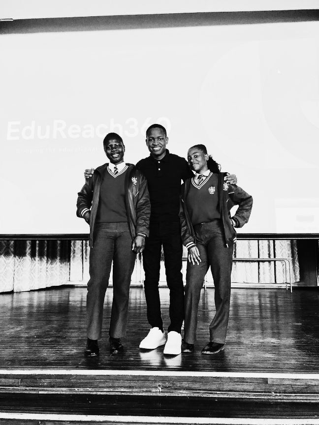 Two learners standing with an EduReach360 facilitator on stage